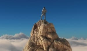 man on top of rock above cloud line