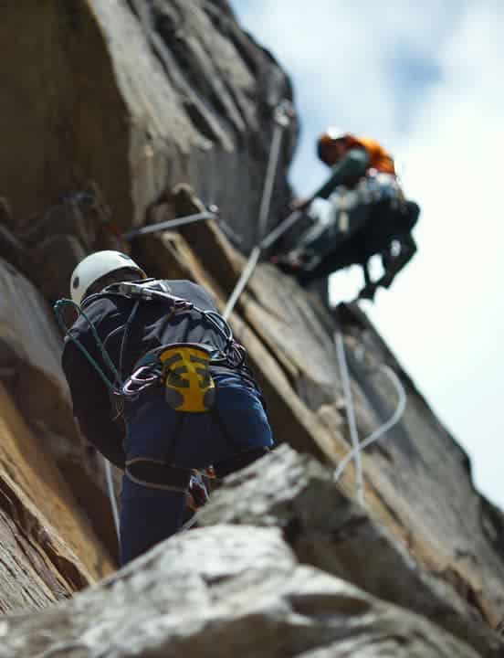 partners climbing up a cliff