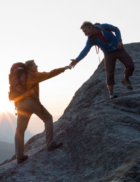 partners helping each other up the mountain