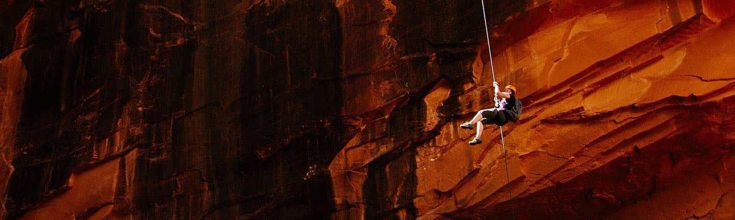 person getting lowered down by rope into cavern