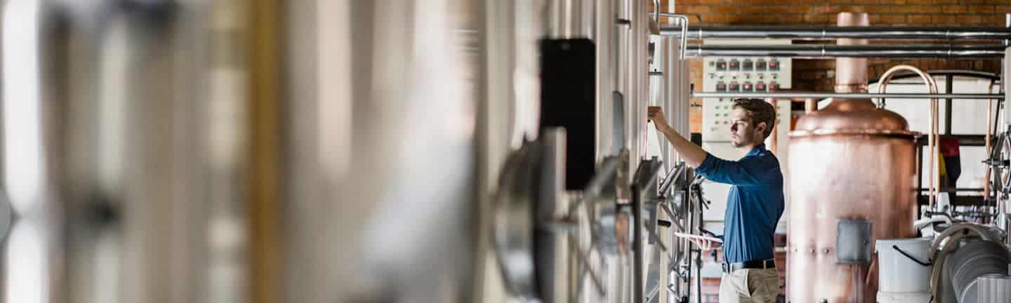 man in beverage industry checking on beer storage tanks