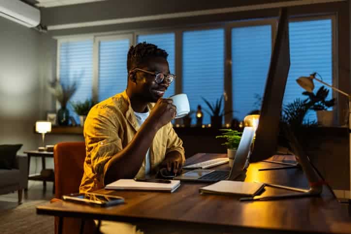 Employee working remotely while drinking coffee.