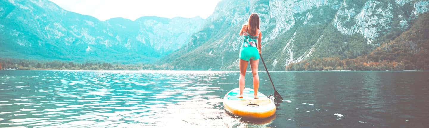 woman paddle boarding in mountain lake