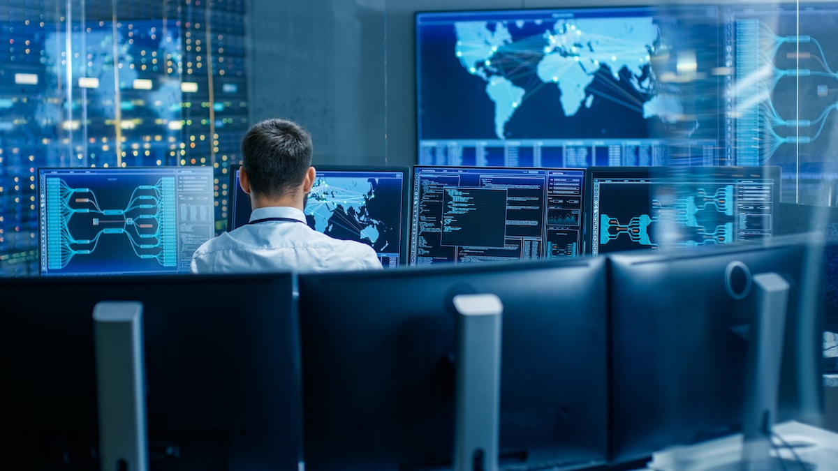 Back View in the System Control Center Operator Working. Multiple Screens Showing Technical Data about Managed Network Services.