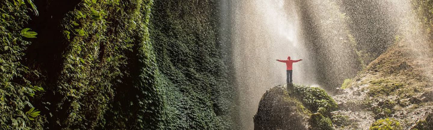 person standing in waterfall drizzle