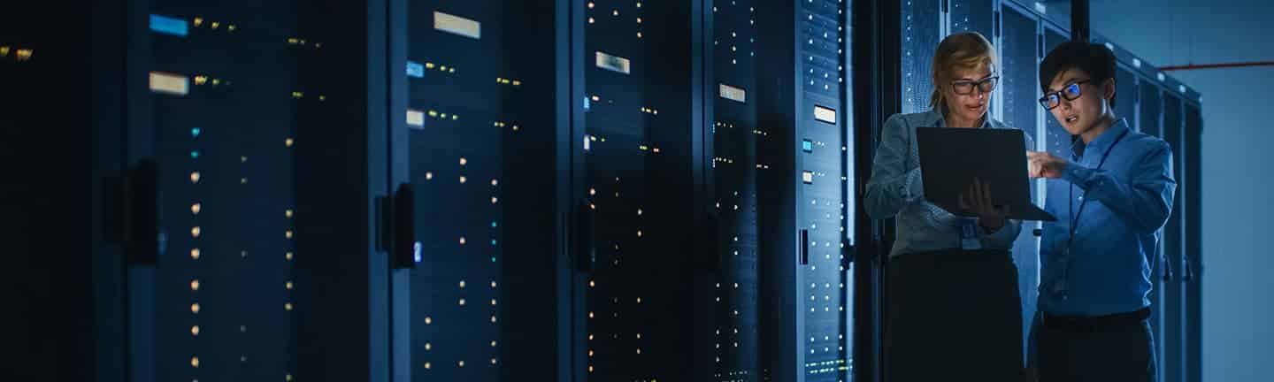 man and woman looking at computer in data center